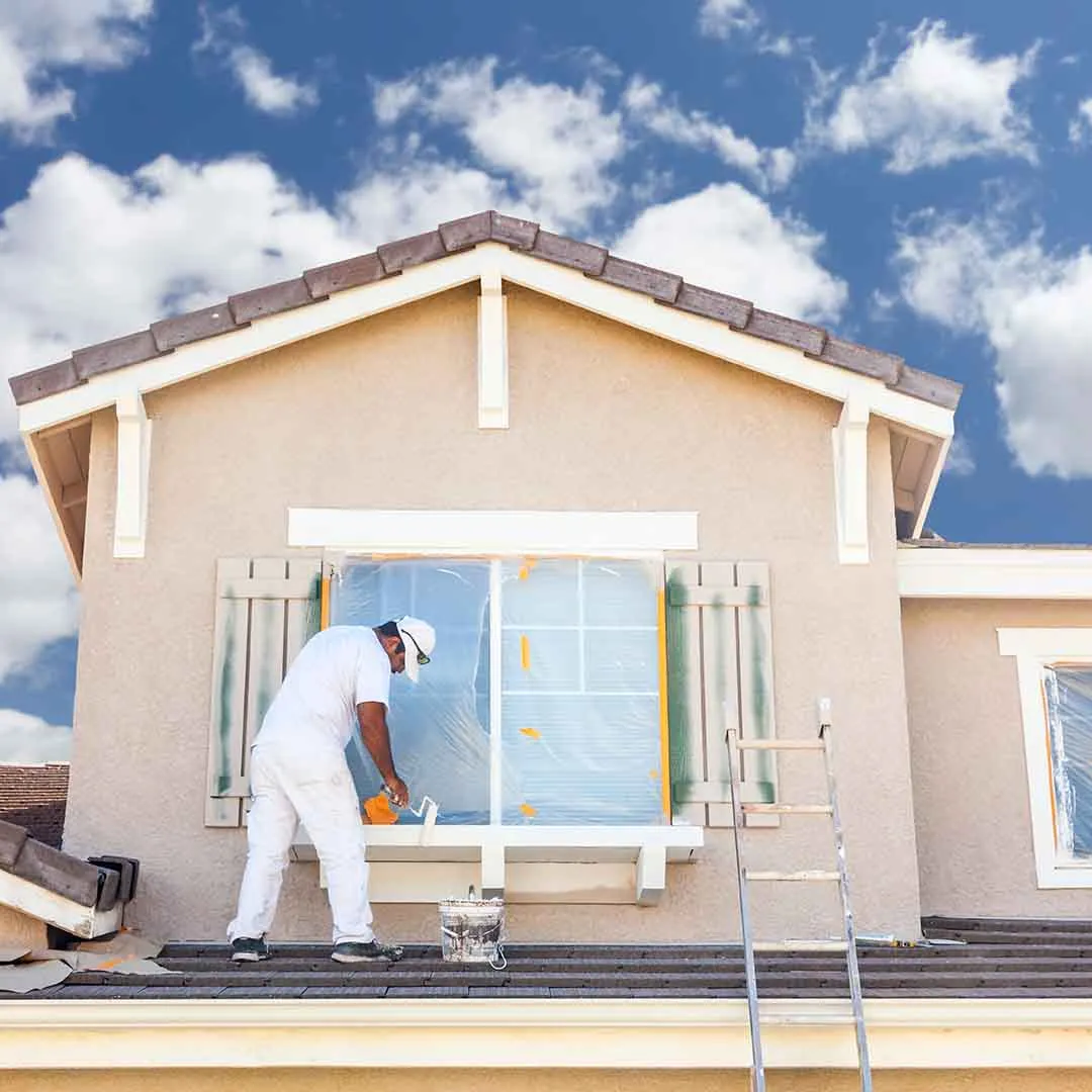 Worker painting a small house exterior