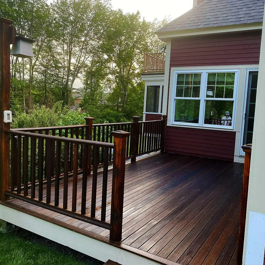 Deck com acabamento em madeira ao lado de parede vermelha