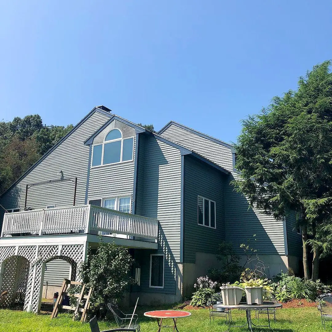 Casa cinza de dois andares com deck sob céu azul