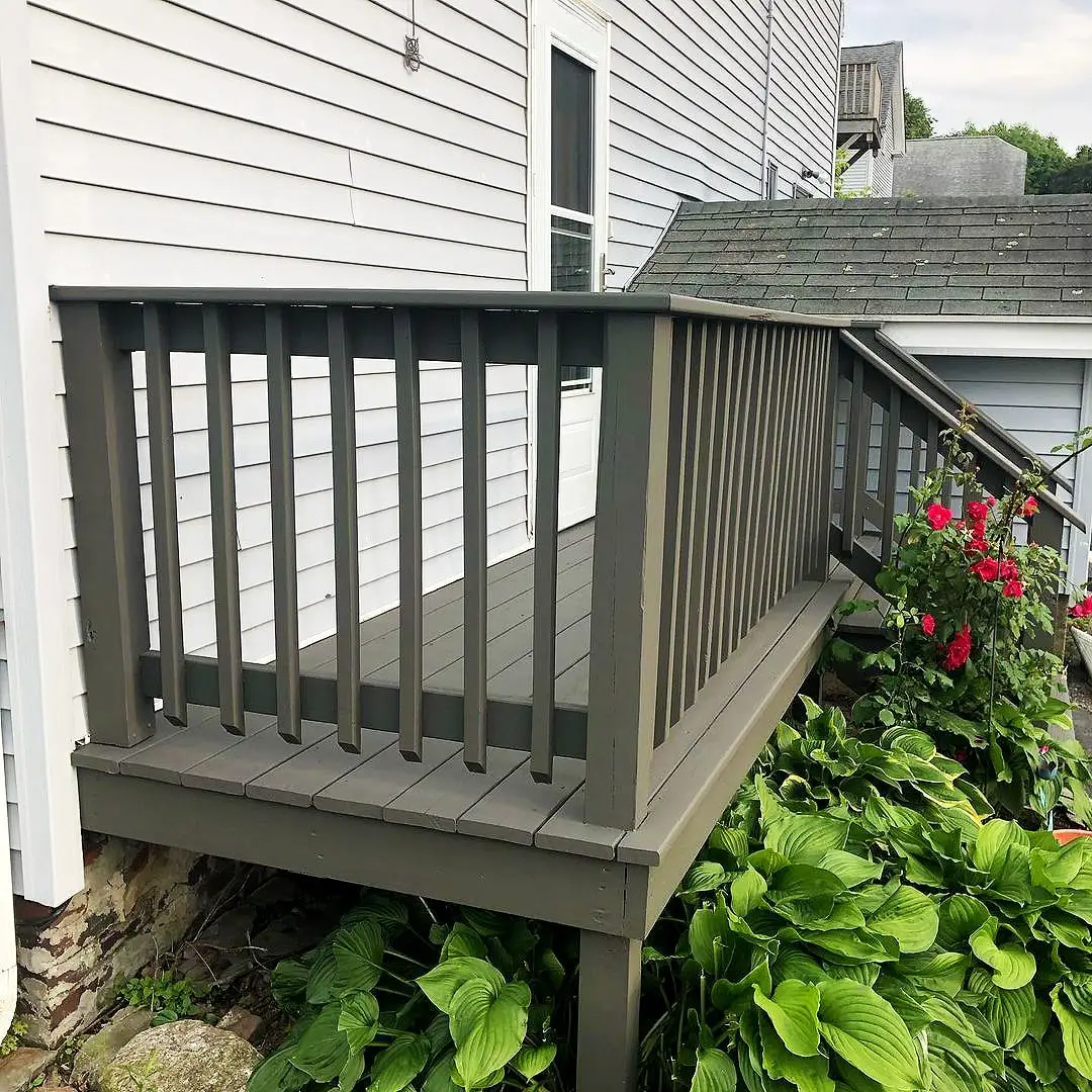 Guarda-corpo cinza de deck junto à parede e plantas