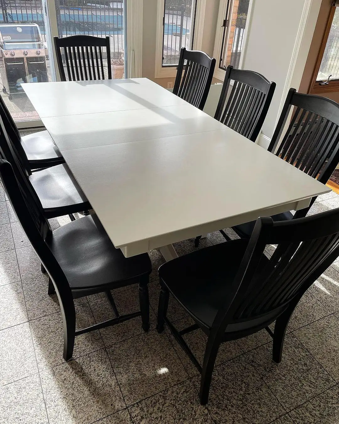 Mesa branca e cadeiras escuras na sala de jantar